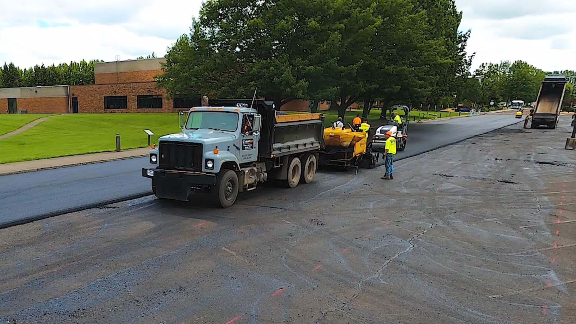 gray dump truck in front of asphalt paving machine