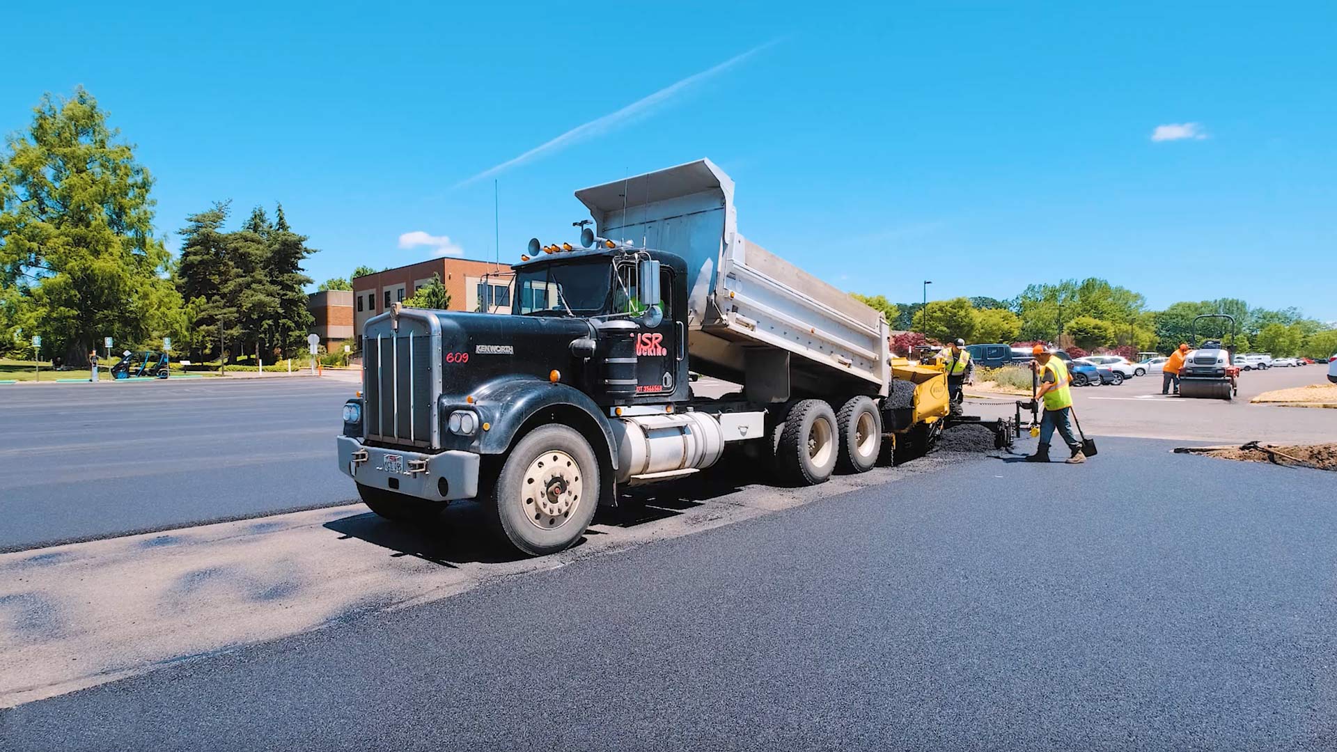 black asphalt dump truck loading asphalt paving machine