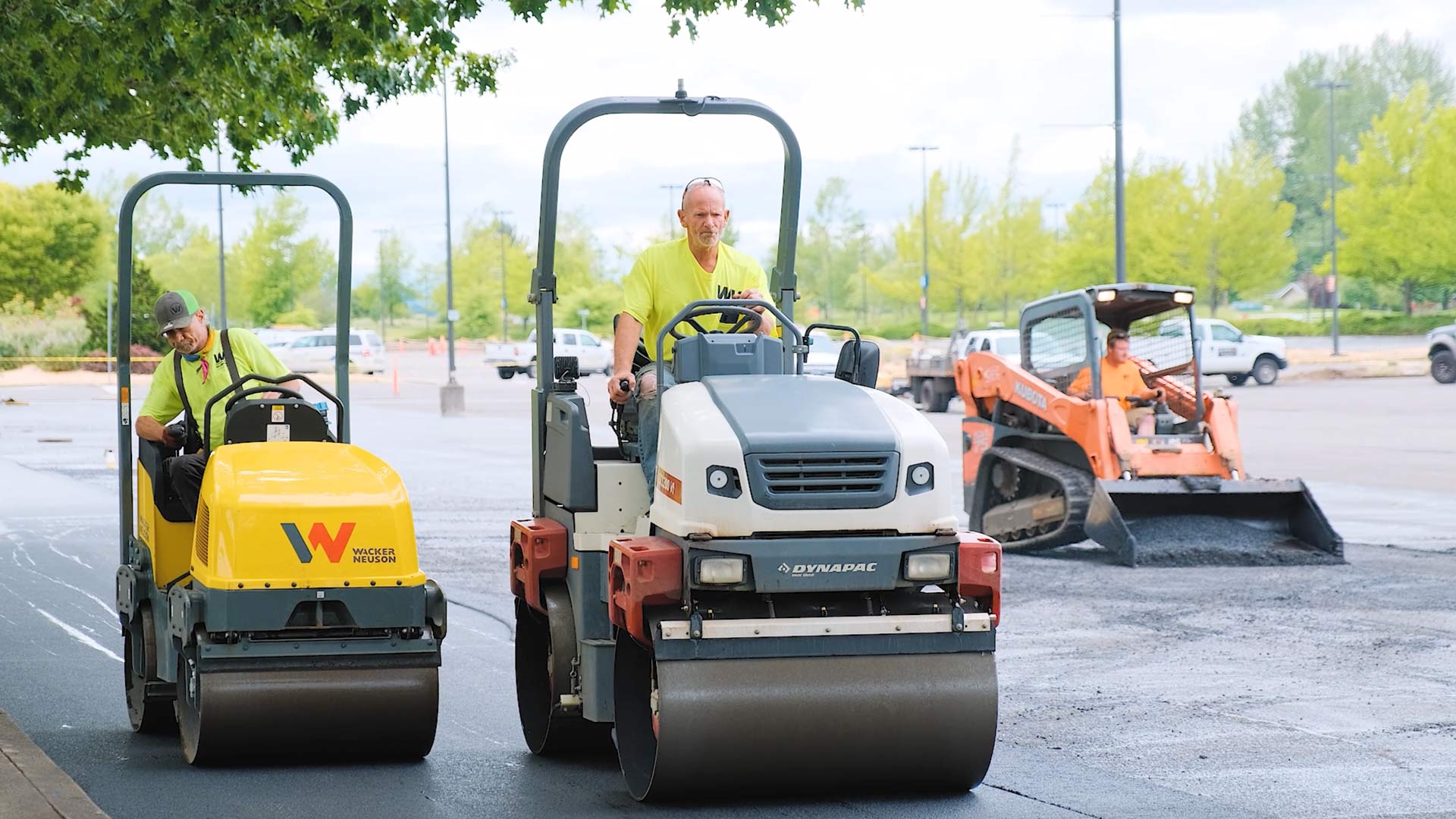 two asphalt paving rollers running side by side over new asphalt