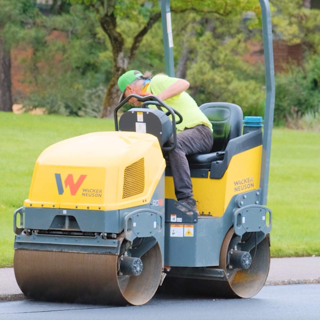 employee on paving roller along curb